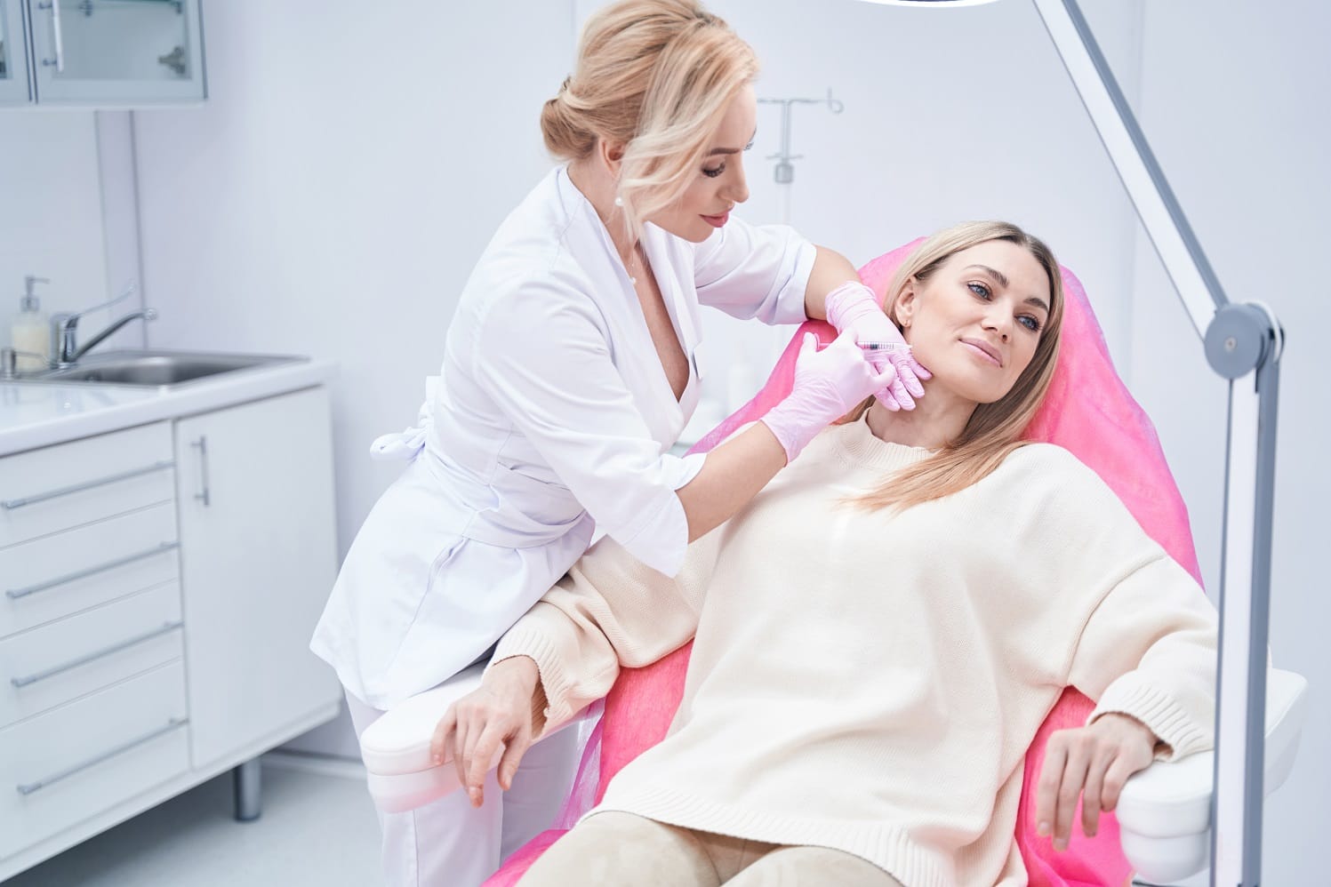 Calm dreamy aesthetic clinic customer sitting in chair during mesotherapy procedure performed by dermatologist. Female patient getting cheek dermal filler injection | Citidrips in Wilmington, DE